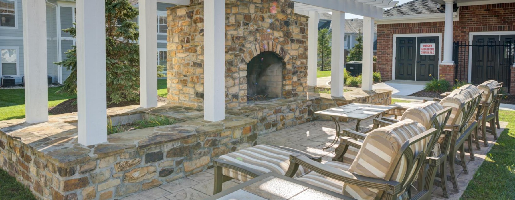 outdoor chairs and tables in front of pergola covered fireplace